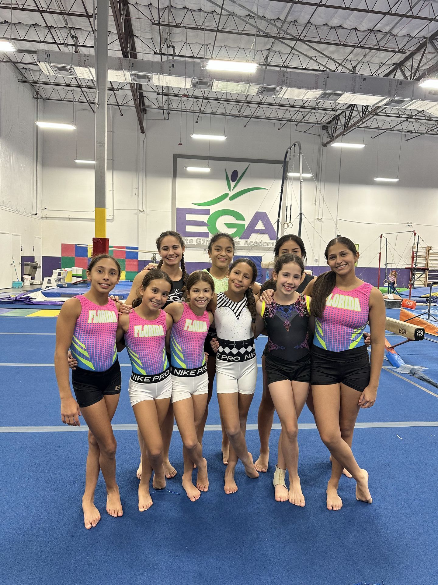 Un grupo de chicas jóvenes posan para una foto en un gimnasio.
