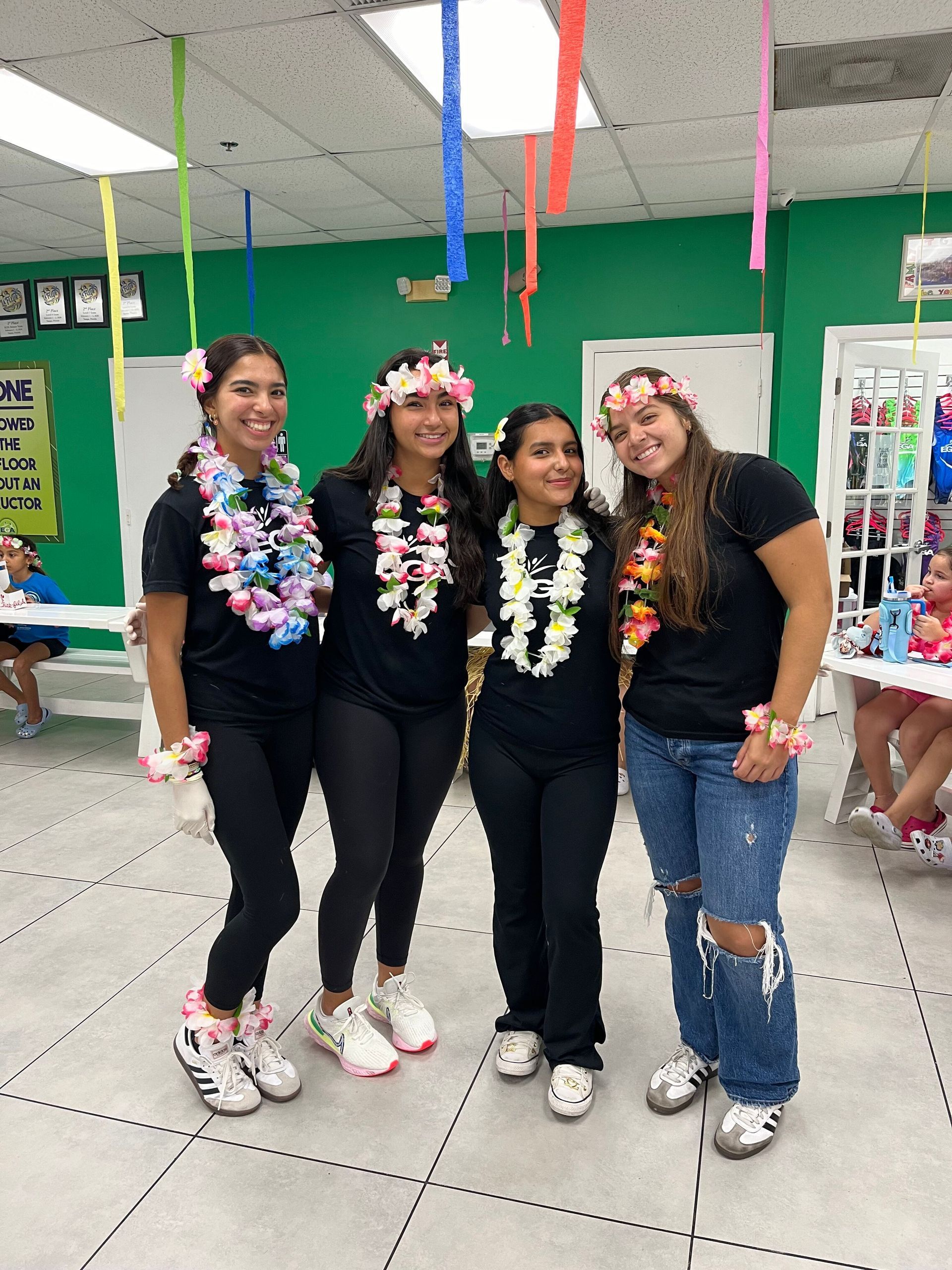 Un grupo de mujeres posan para una fotografía en una habitación con flores en el pelo.