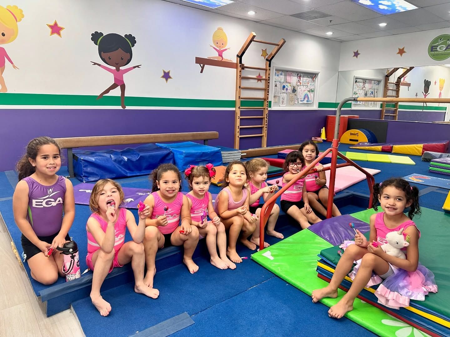 Un grupo de chicas jóvenes están sentadas en un banco en un gimnasio.