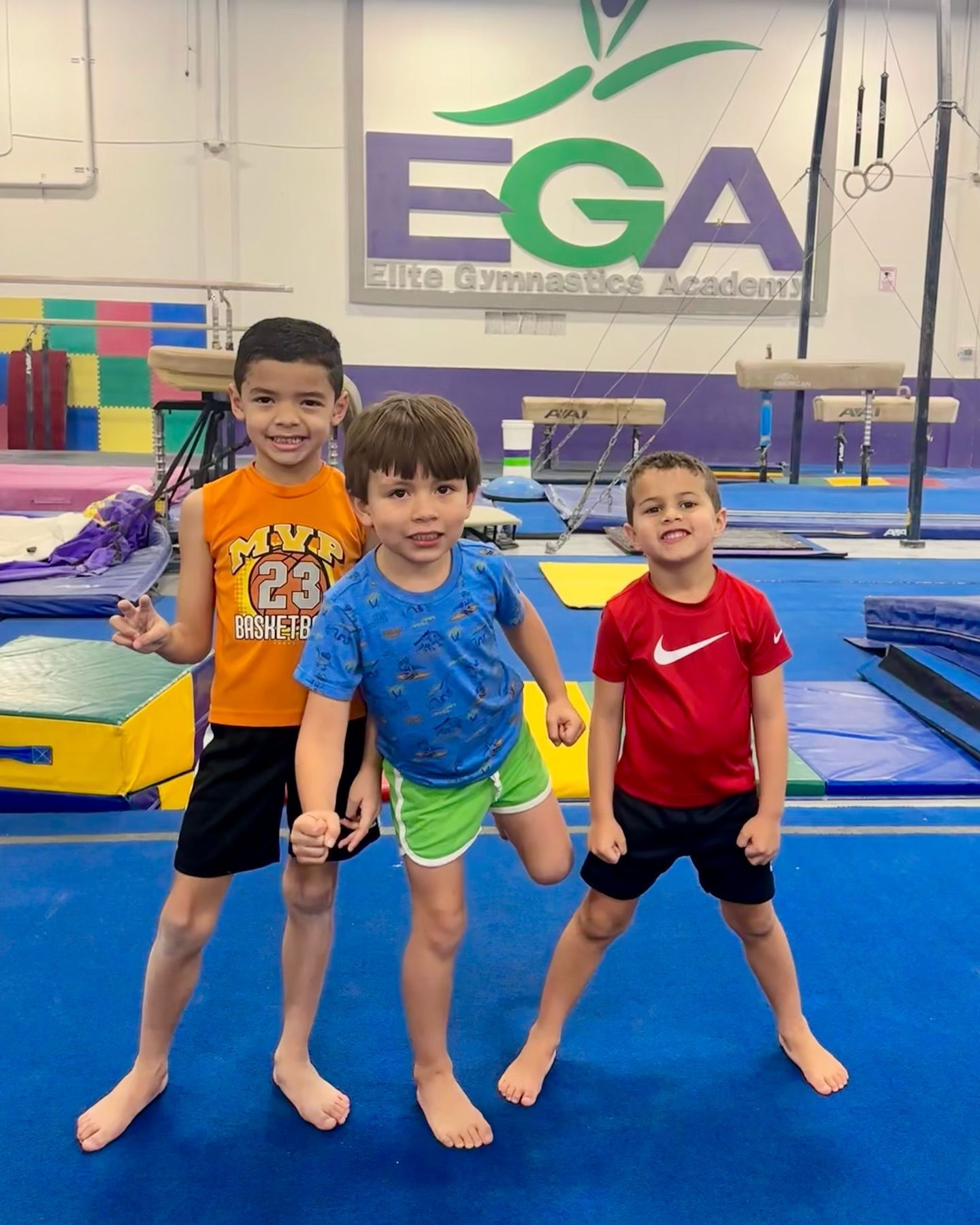 Tres jóvenes posan para una foto frente a un cartel que dice ega