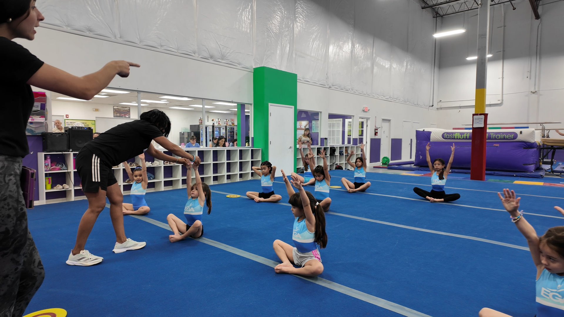 Un grupo de chicas jóvenes está haciendo ejercicios de estiramiento en un gimnasio.