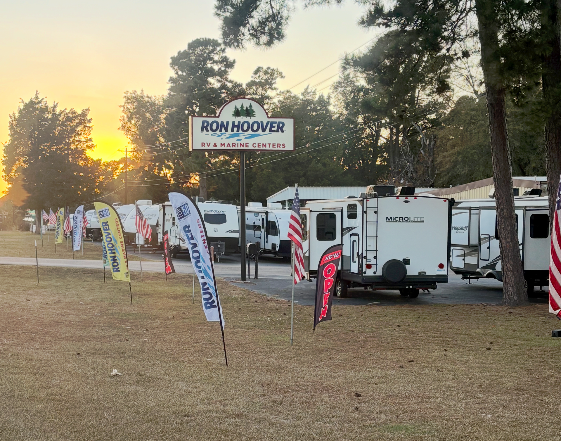 RV dealership with multiple trailers, flags, and a sign that says 