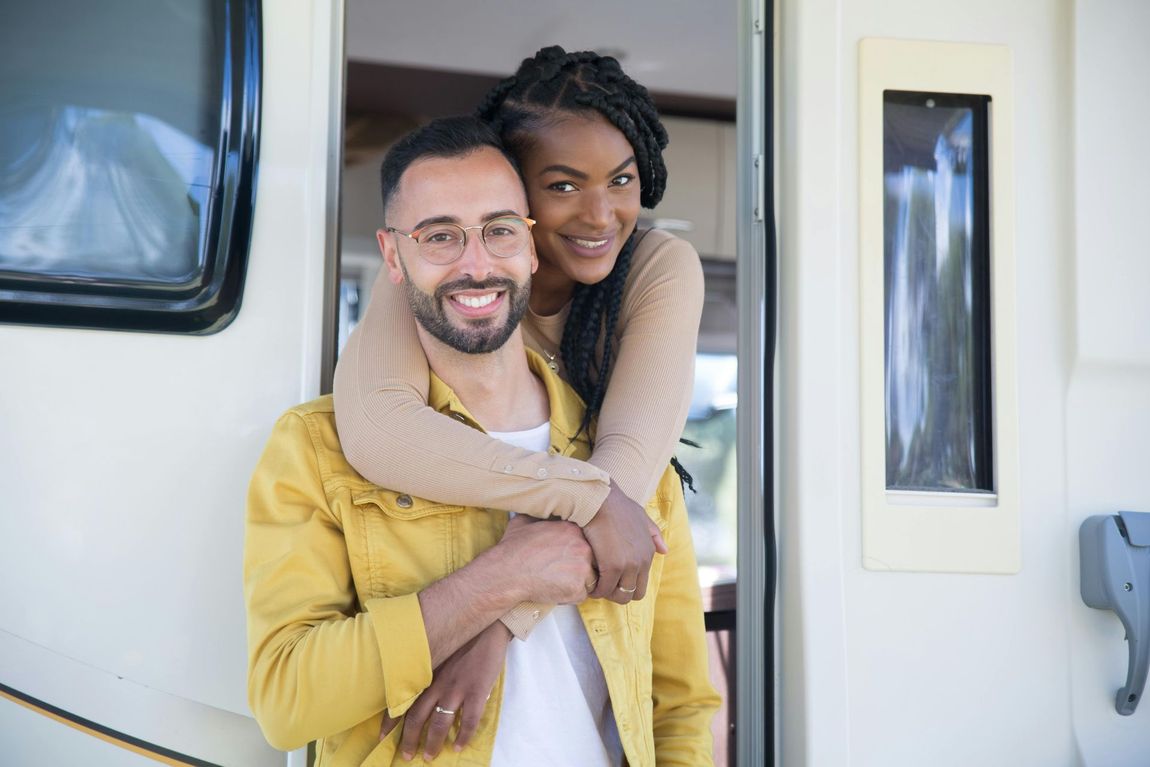 Couple embracing inside a recreational vehicle; smiling, warm tones.