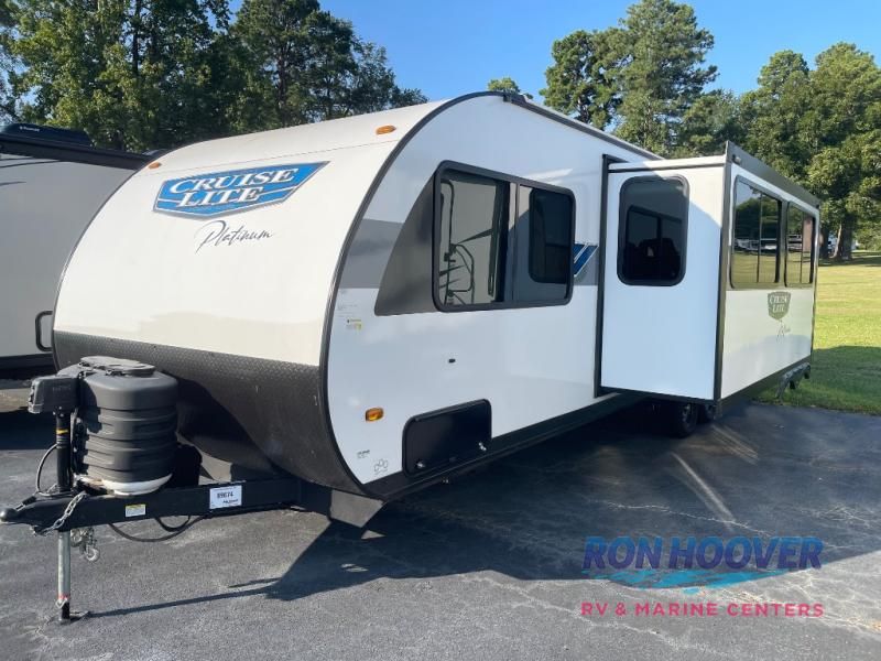 White and gray travel trailer with slide-out extended, parked on pavement.