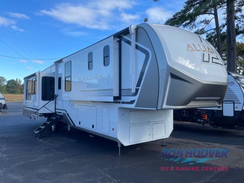 White and gray Alliance RV parked outside, with slides extended.