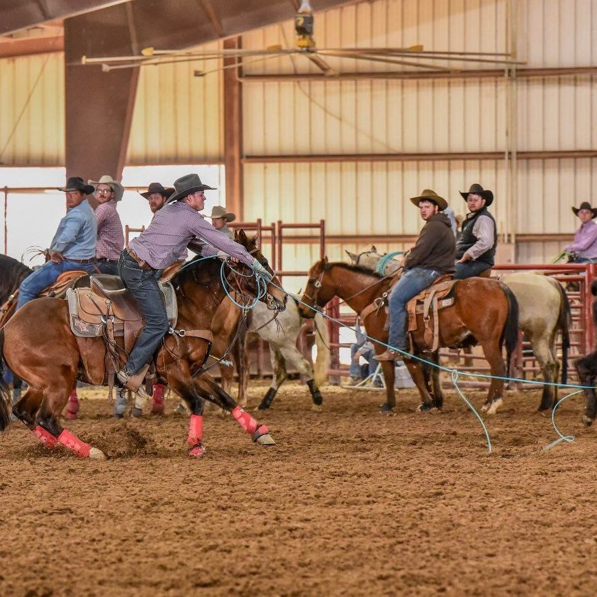 A group of cowboys are riding horses in an arena