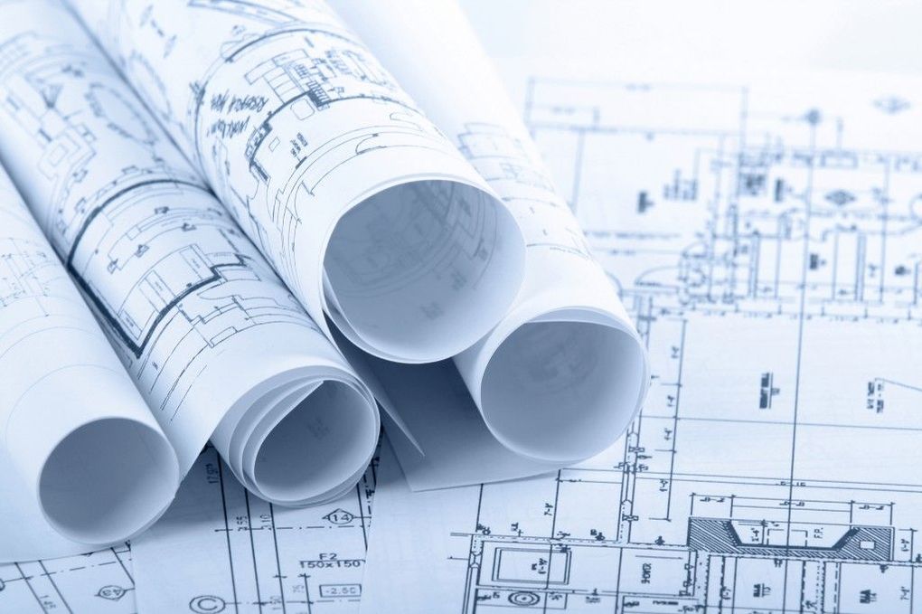 Several blueprints rolled up, resting on top of a flat, technical architectural drawing.
