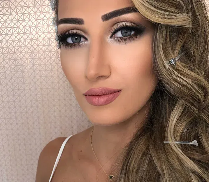 Woman with smoky eye makeup and wavy blonde hair, looking at the camera.