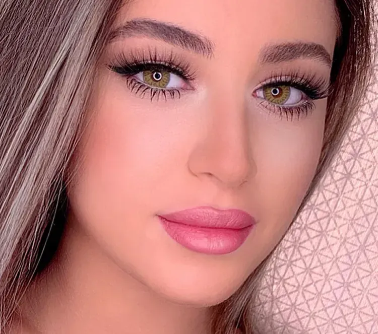 Woman with green eyes, wearing makeup, looking at the camera.