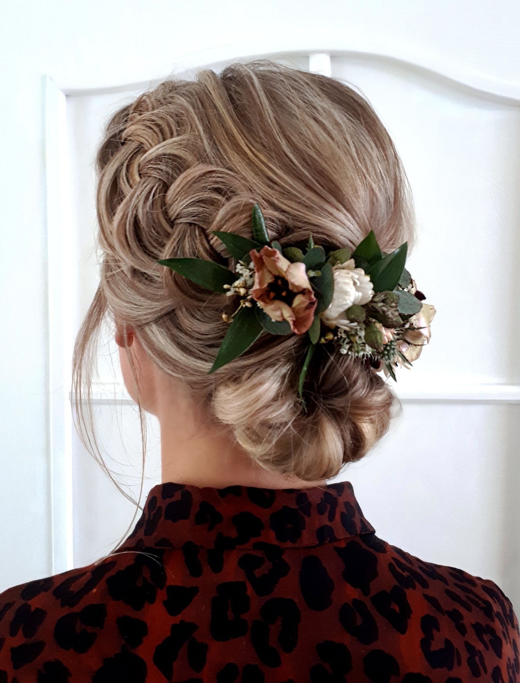 Vintage opsteekkapsel, lage knot met vlecht aan de zijkant en droge bloemen in haar. Een favoriete bruidskapsel