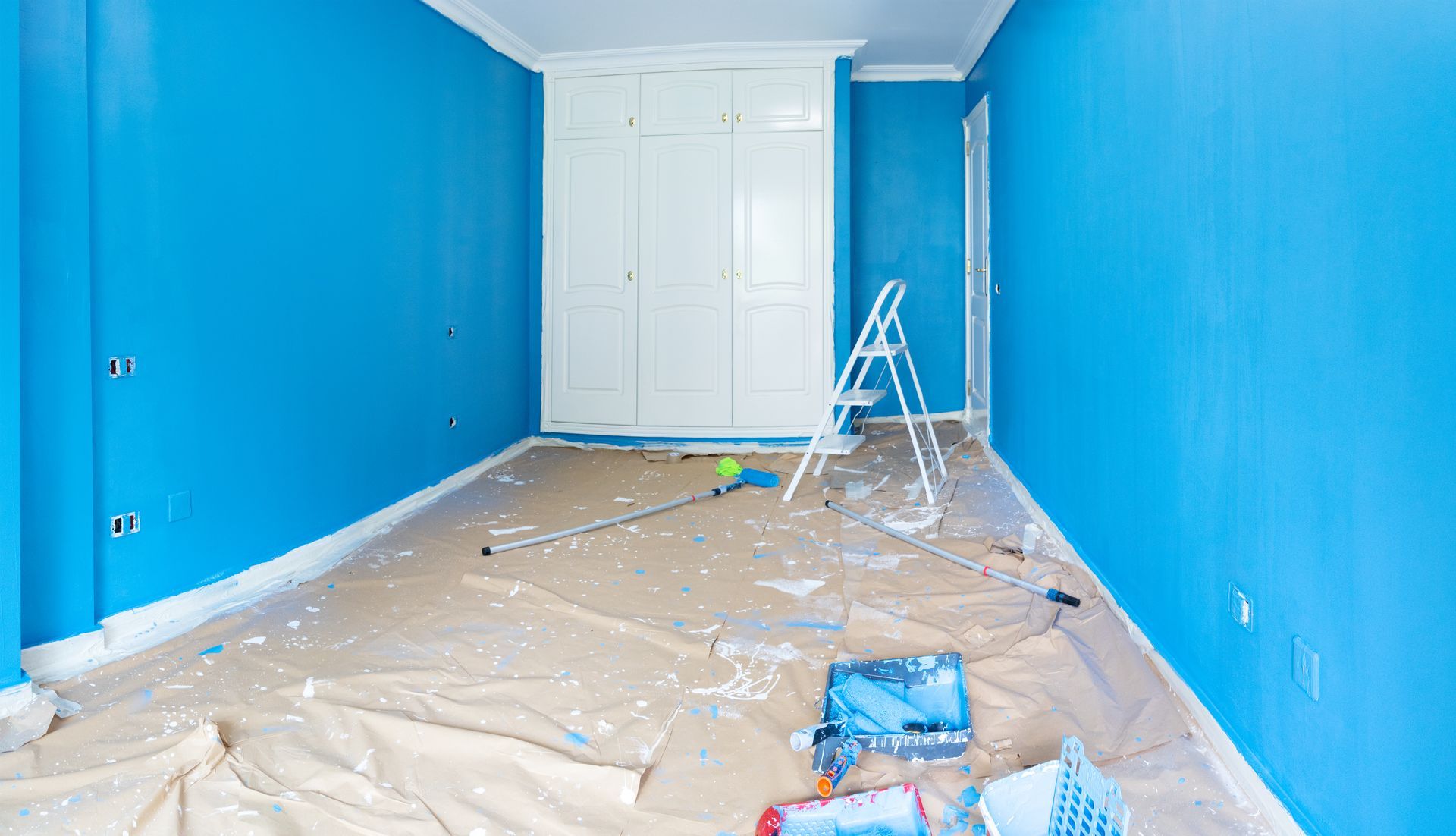 Room interior being painted blue, with white trim and closet. Paint supplies and ladder on floor.