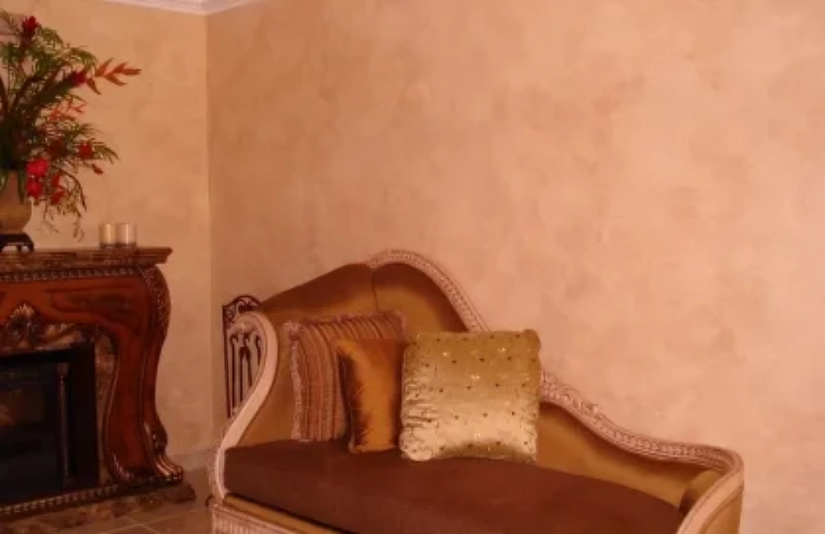 A chaise lounge and fireplace in a room with textured peach walls.