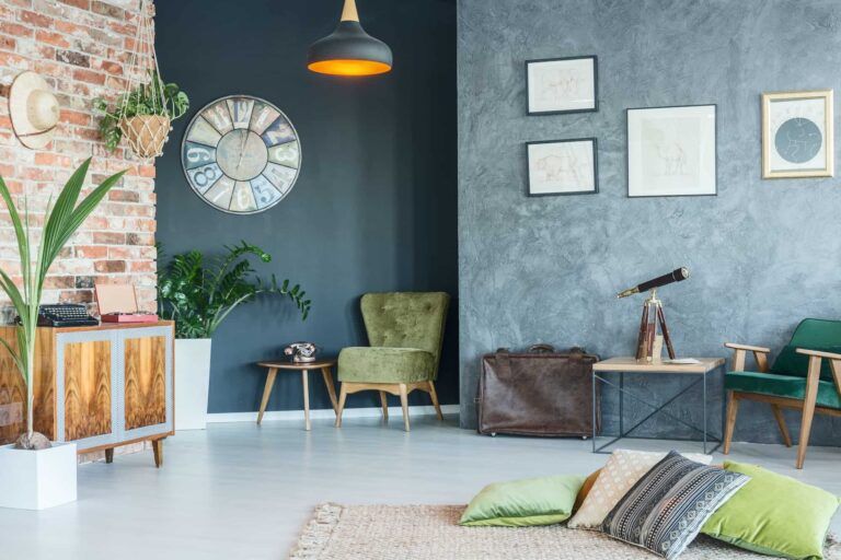 Living room with exposed brick, dark blue walls, plants, vintage furniture, and artwork.