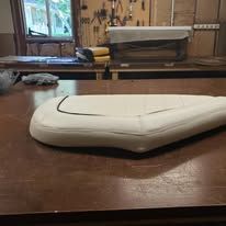 White, curved boat seat with black trim on a wooden table.