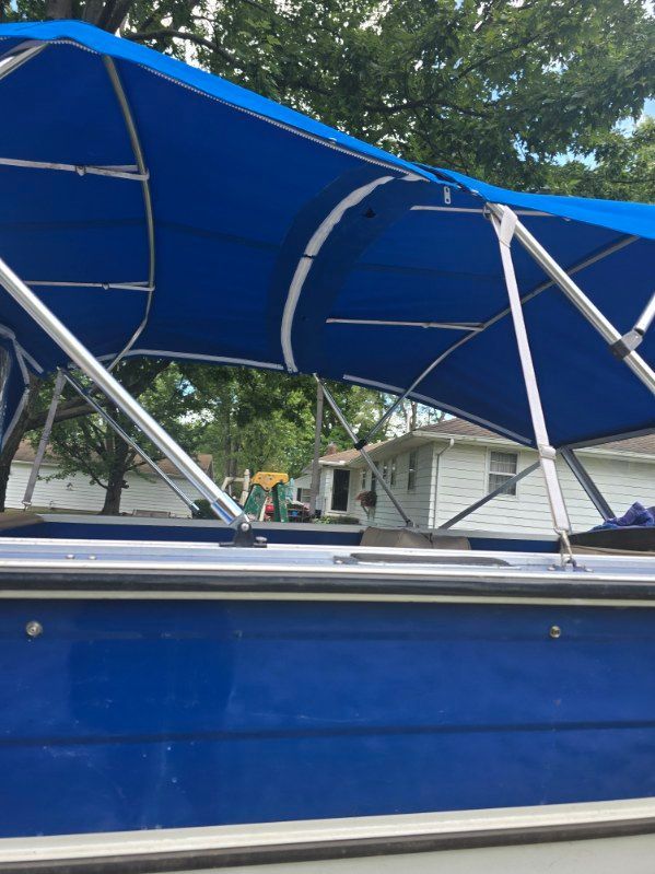 Blue boat with a blue canopy. The canopy is supported by silver metal poles.