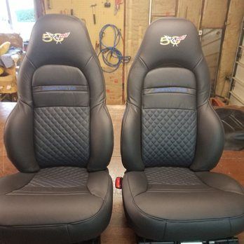 Two black car seats with diamond-stitched blue inserts, the Corvette logo, and blue trim.