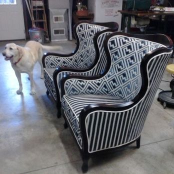 Two stylish armchairs with black frames and patterned upholstery, a dog in the background.