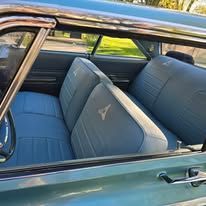 Interior of a vintage turquoise car; light blue seats, chrome trim.