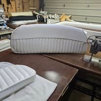 A gray upholstered boat seat on a wooden table in a workshop.