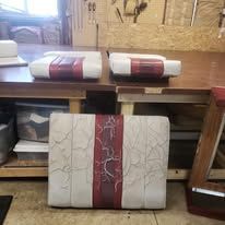 Four upholstered panels, beige with red stripe, on a workbench.