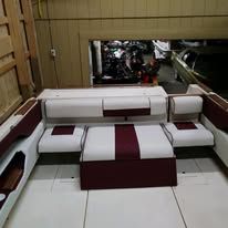 Interior of a boat with white and burgundy seats.