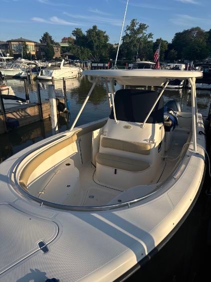 White motorboat docked at a marina with tan seating and a white canopy.