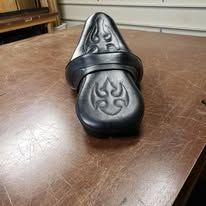 Black leather motorcycle seat with embossed tribal flame design.