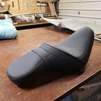 Black motorcycle seat on a wooden table.