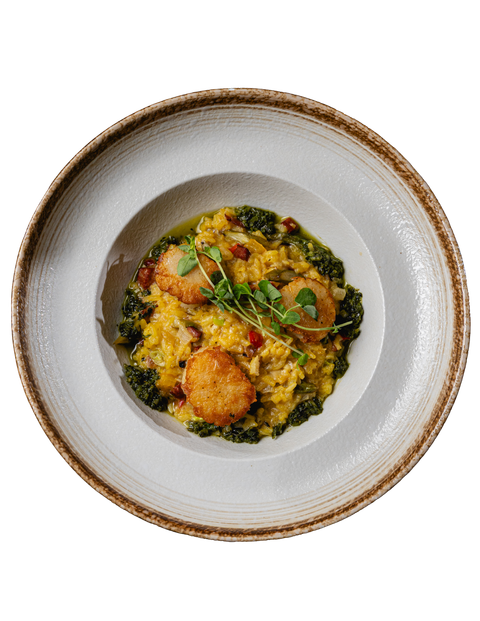 Overhead view of a plated grain bowl with roasted vegetables and greens in a white bowl