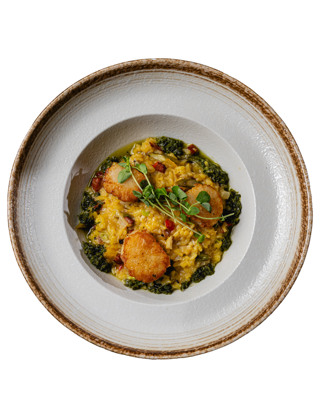 Overhead view of a plated grain bowl with roasted vegetables and greens in a white bowl