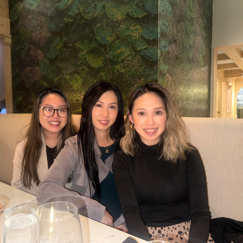 Three women are posing for a picture while sitting at a booth