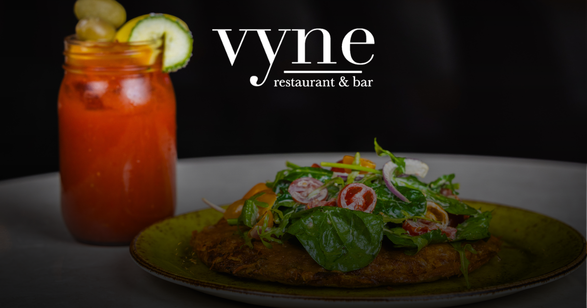 Plated gourmet dish beside a red cocktail in a restaurant ad with the Vyne logo