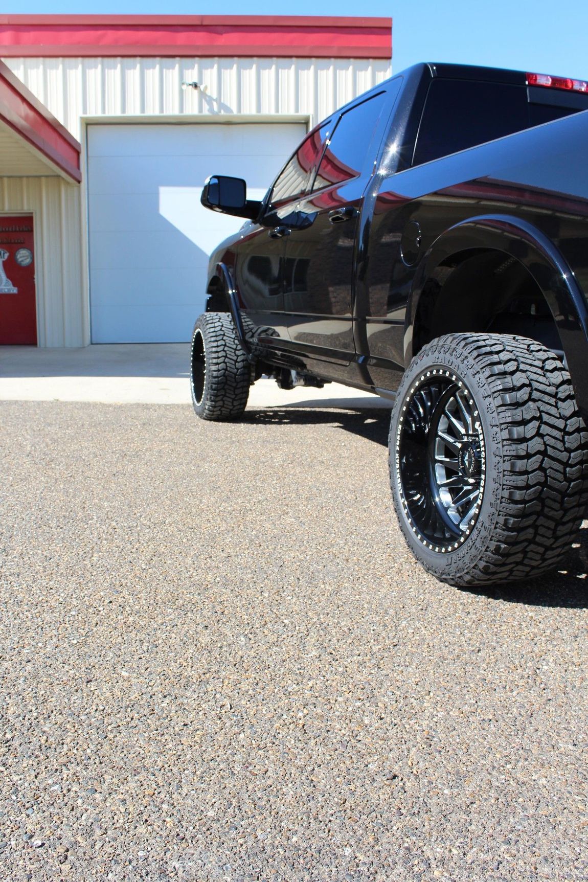 A black truck is parked in front of a garage door.