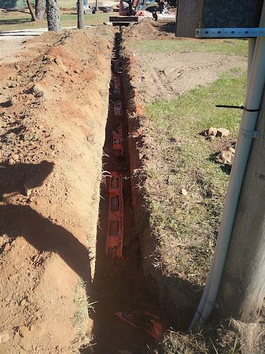 A Brick Wall Is Being Built In The Dirt Next To A Pole — Ant's Earthworks In North Deep Creek, QLD