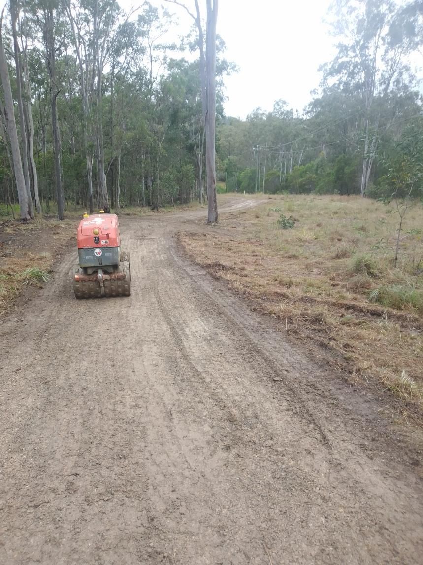 A Bulldozer Is Driving Down A Dirt Road In The Woods — Ant's Earthworks In North Deep Creek, QLD