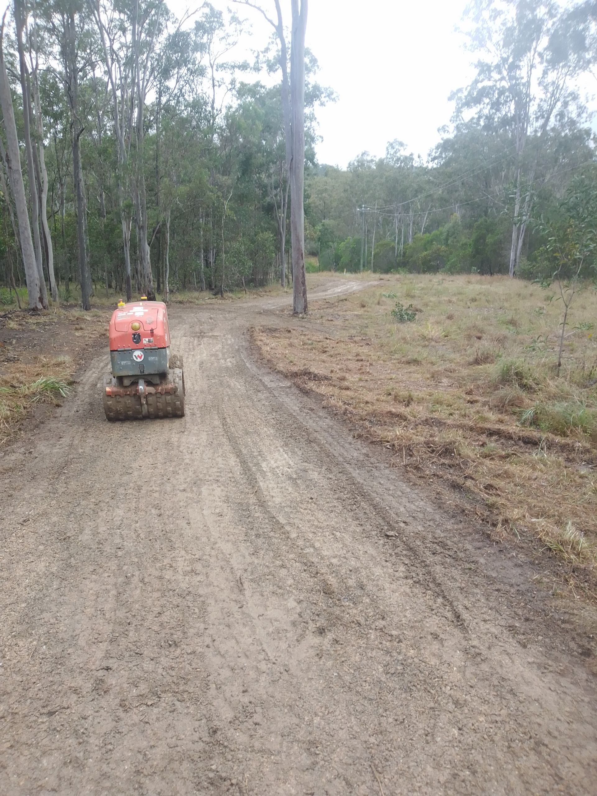 A Roller Is Working On A Dirt Road — Ant's Earthworks In North Deep Creek, QLD