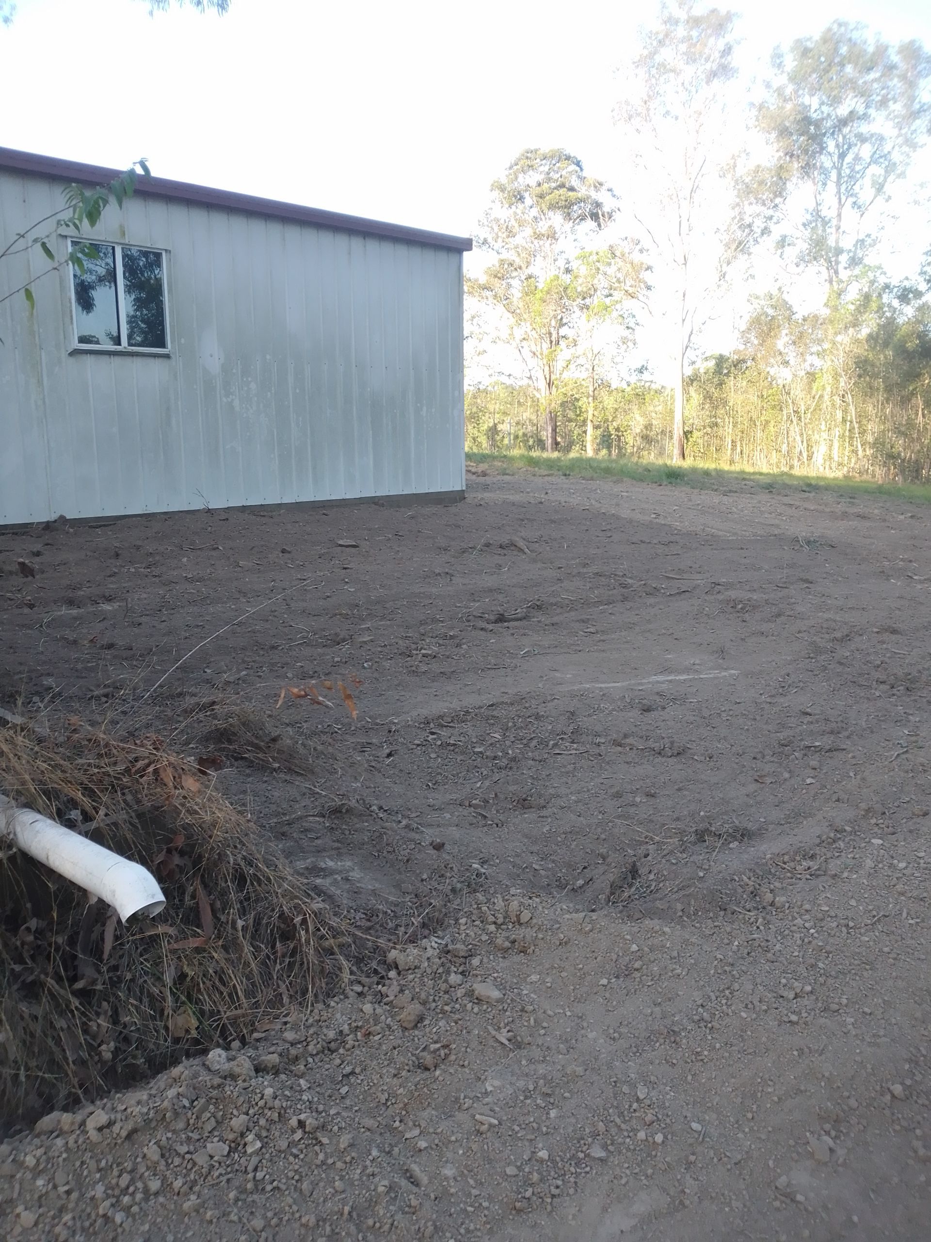 A White Building Is Sitting In The Middle Of A Dirt Field — Ant's Earthworks In North Deep Creek, QLD
