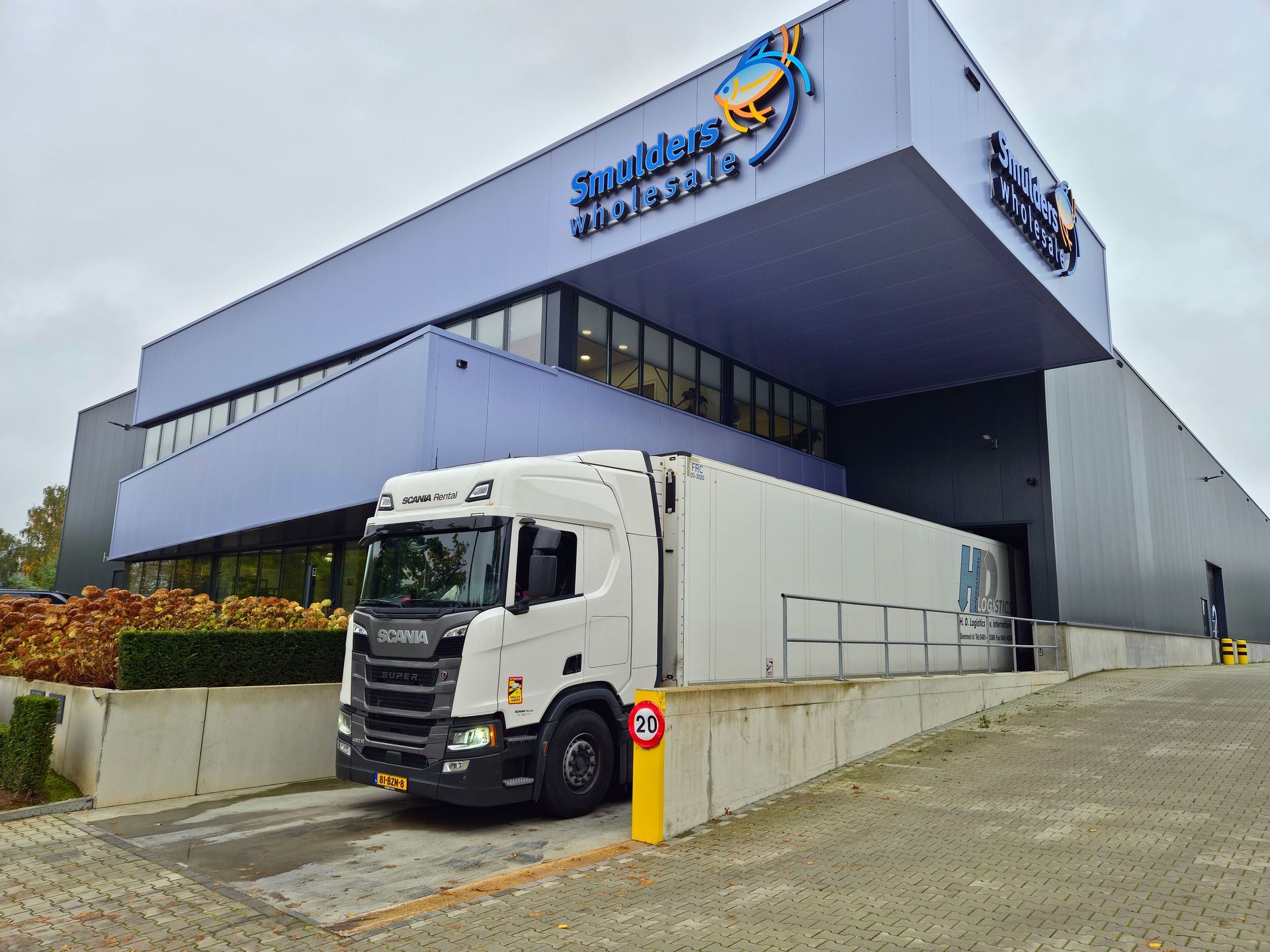 Een witte vrachtwagen staat bij het laadperron van een groothandelspand van 