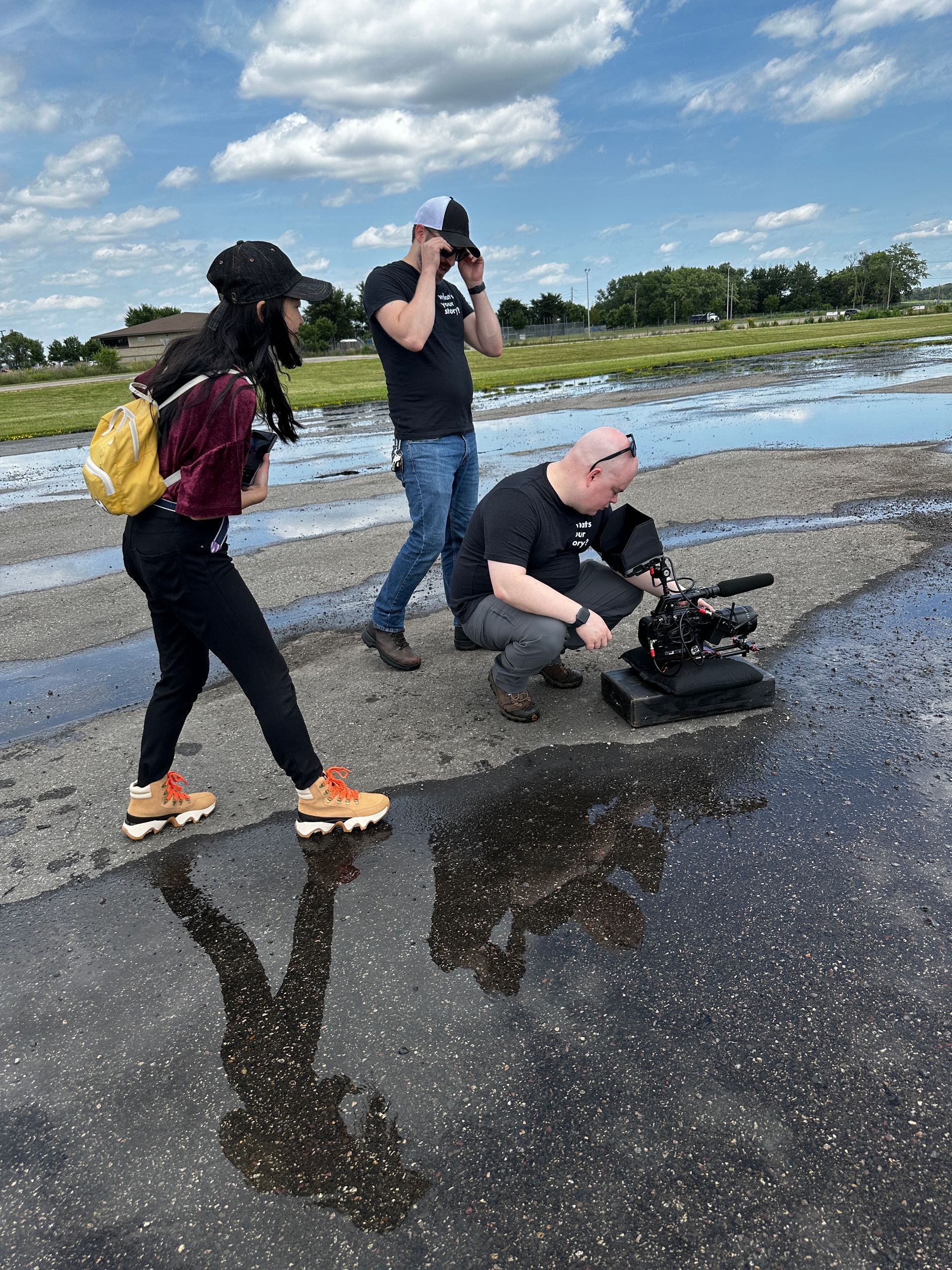 A group of people are standing on a wet road.
