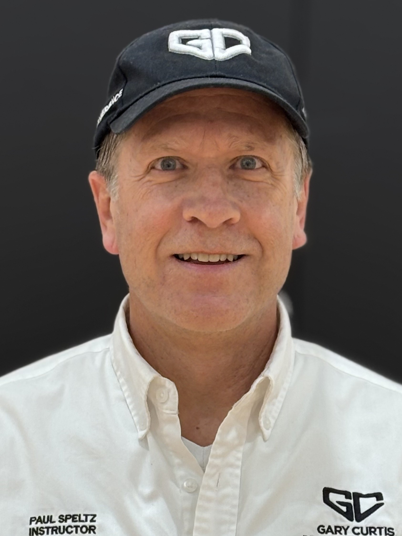 Man wearing black cap, white shirt, smiling, with 