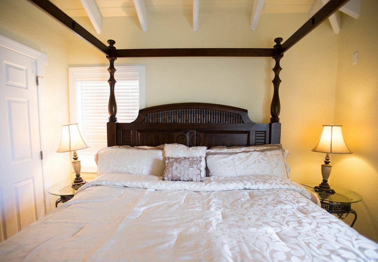 A bedroom with a four poster bed and two lamps