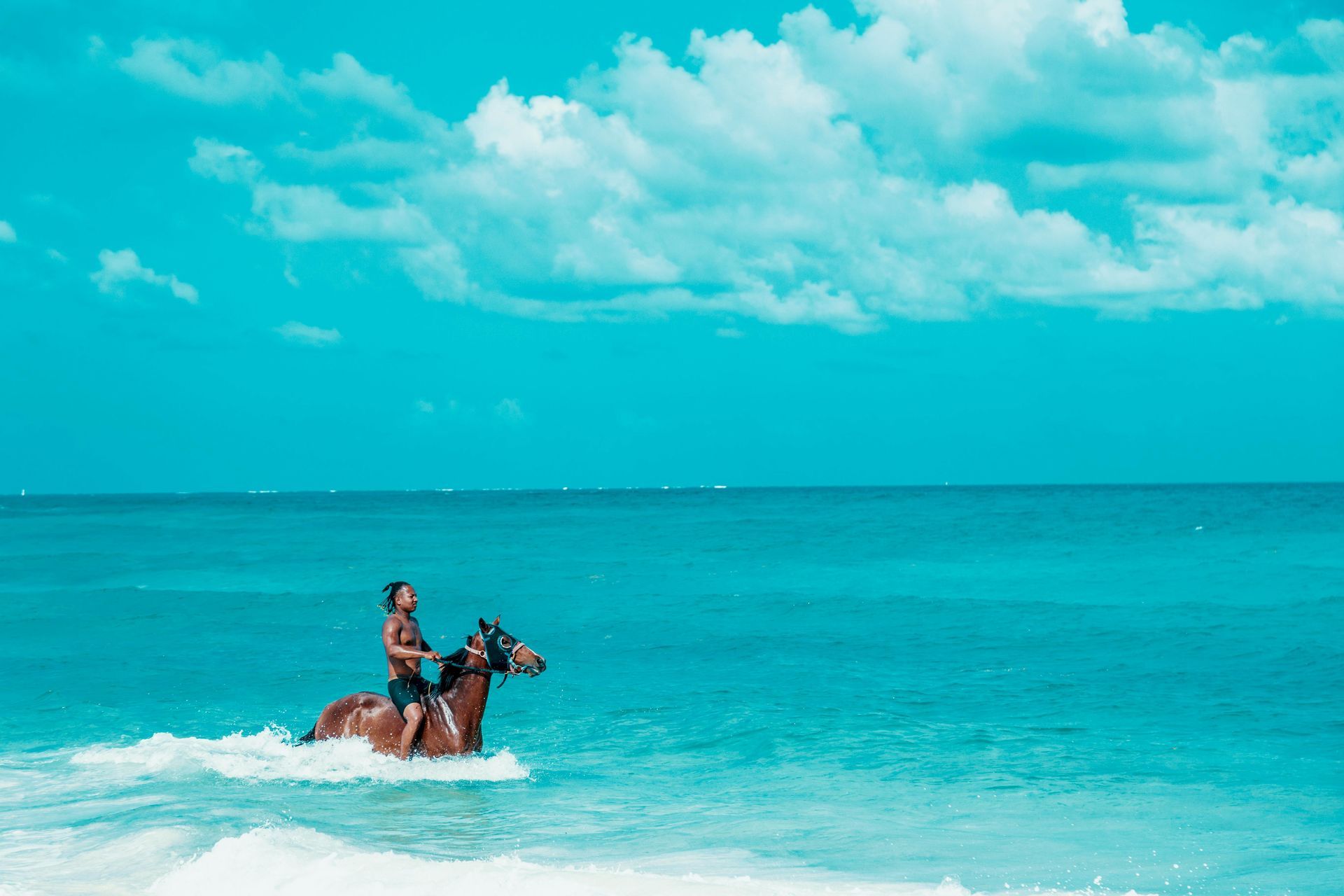 A man is riding a horse in the ocean.