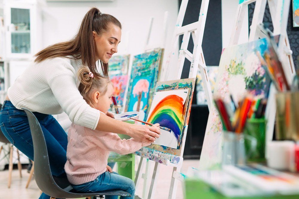 Teacher helping a girl to paint — Diploma of Early Childhood Education & Care in Queensland in Kingaroy, QLD
