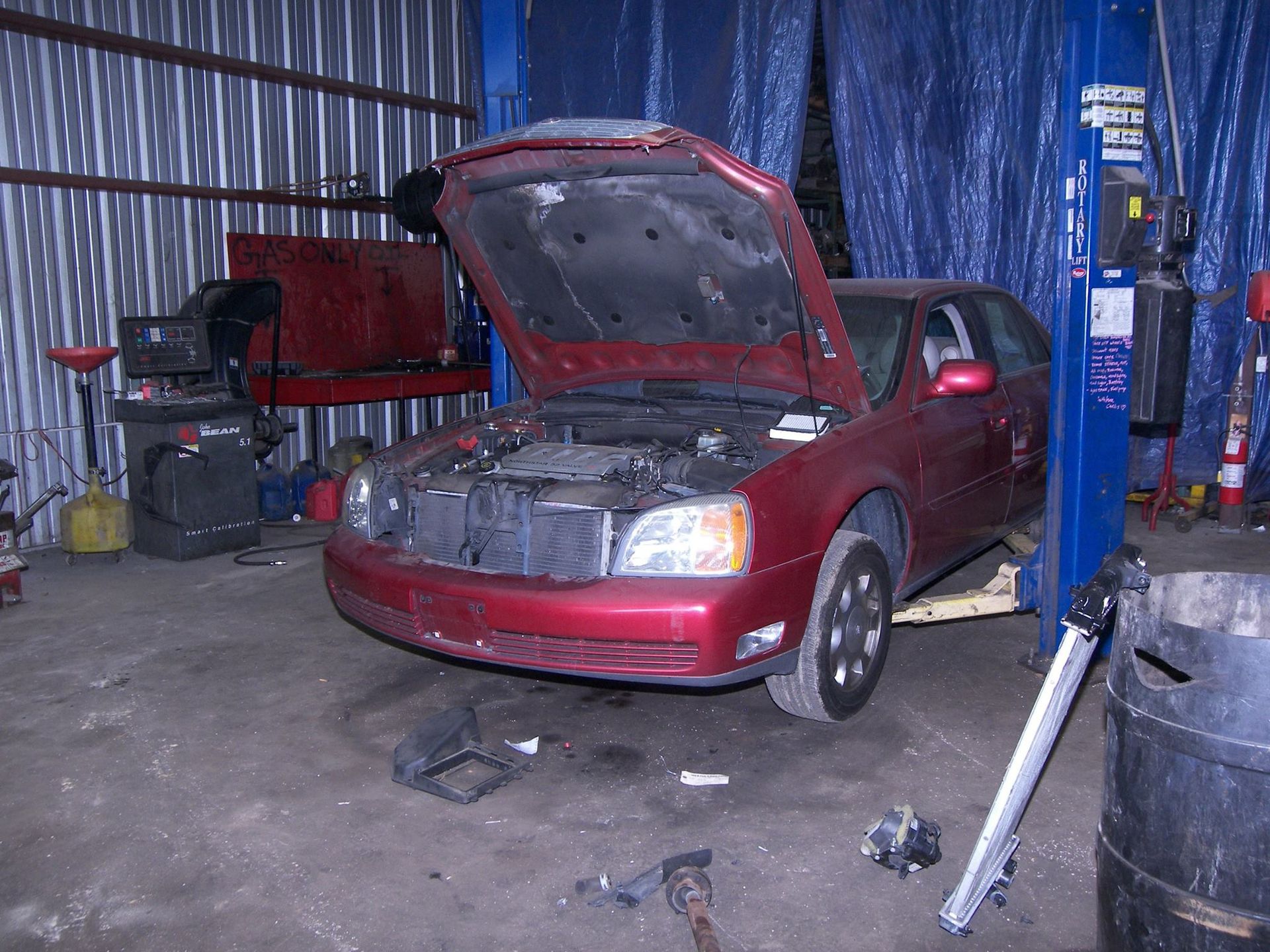 A red car with the hood up in a garage