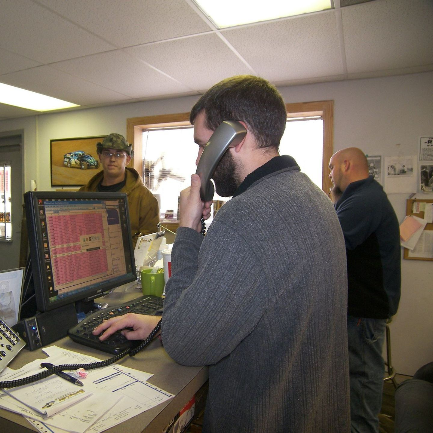 A man talking on a cell phone in front of a computer