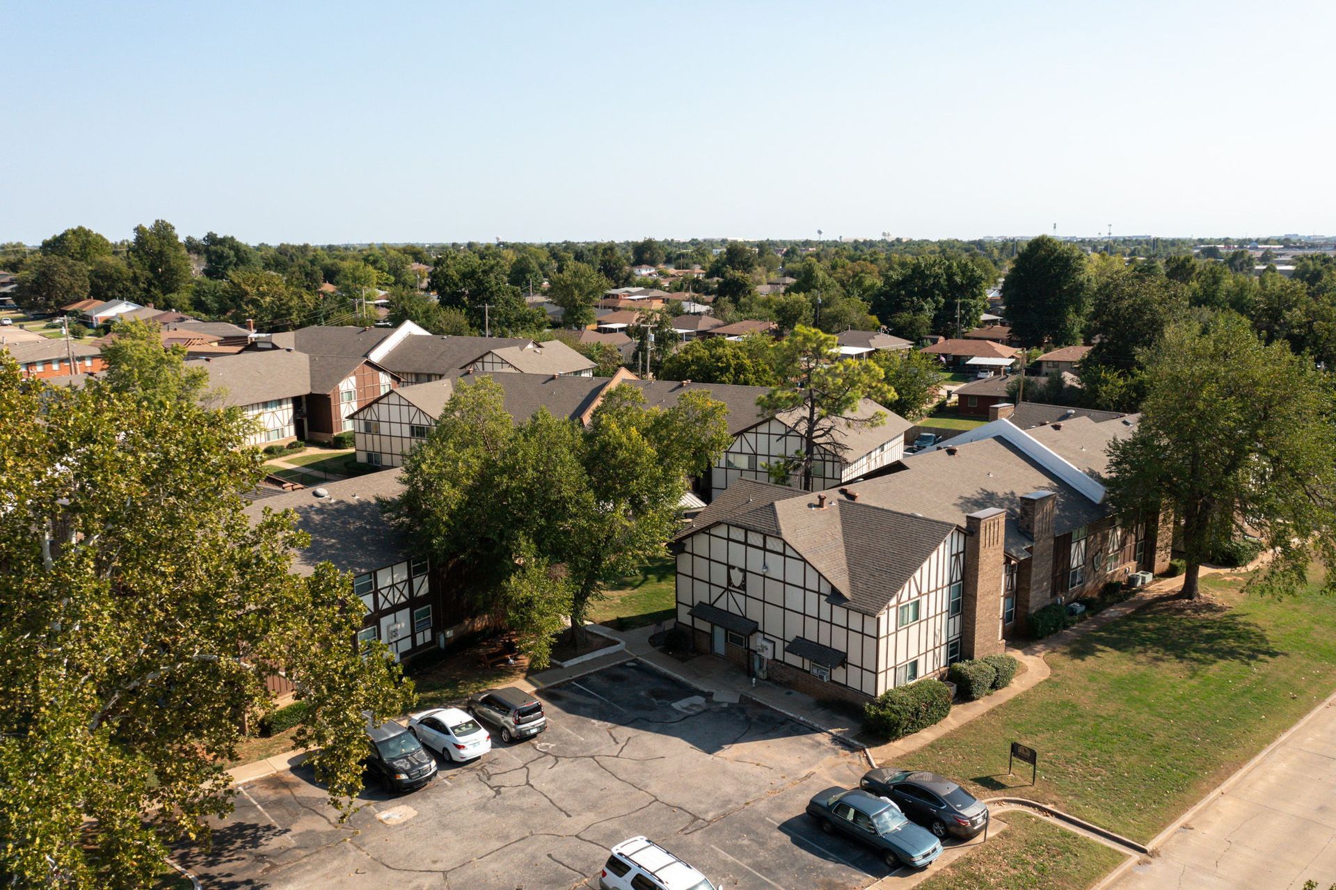 An aerial view of a apartment complex with cars parked in front of it.