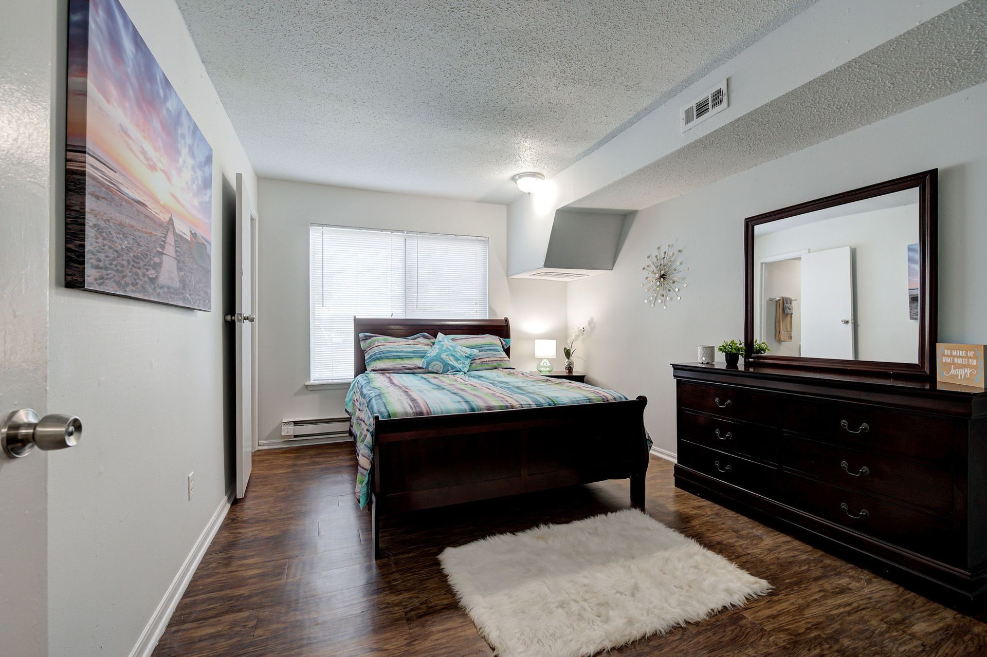 A bedroom with a bed , dresser and mirror