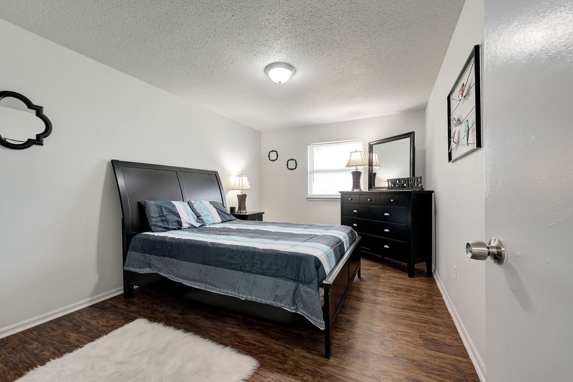 A bedroom with a bed , dresser , mirror and rug.
