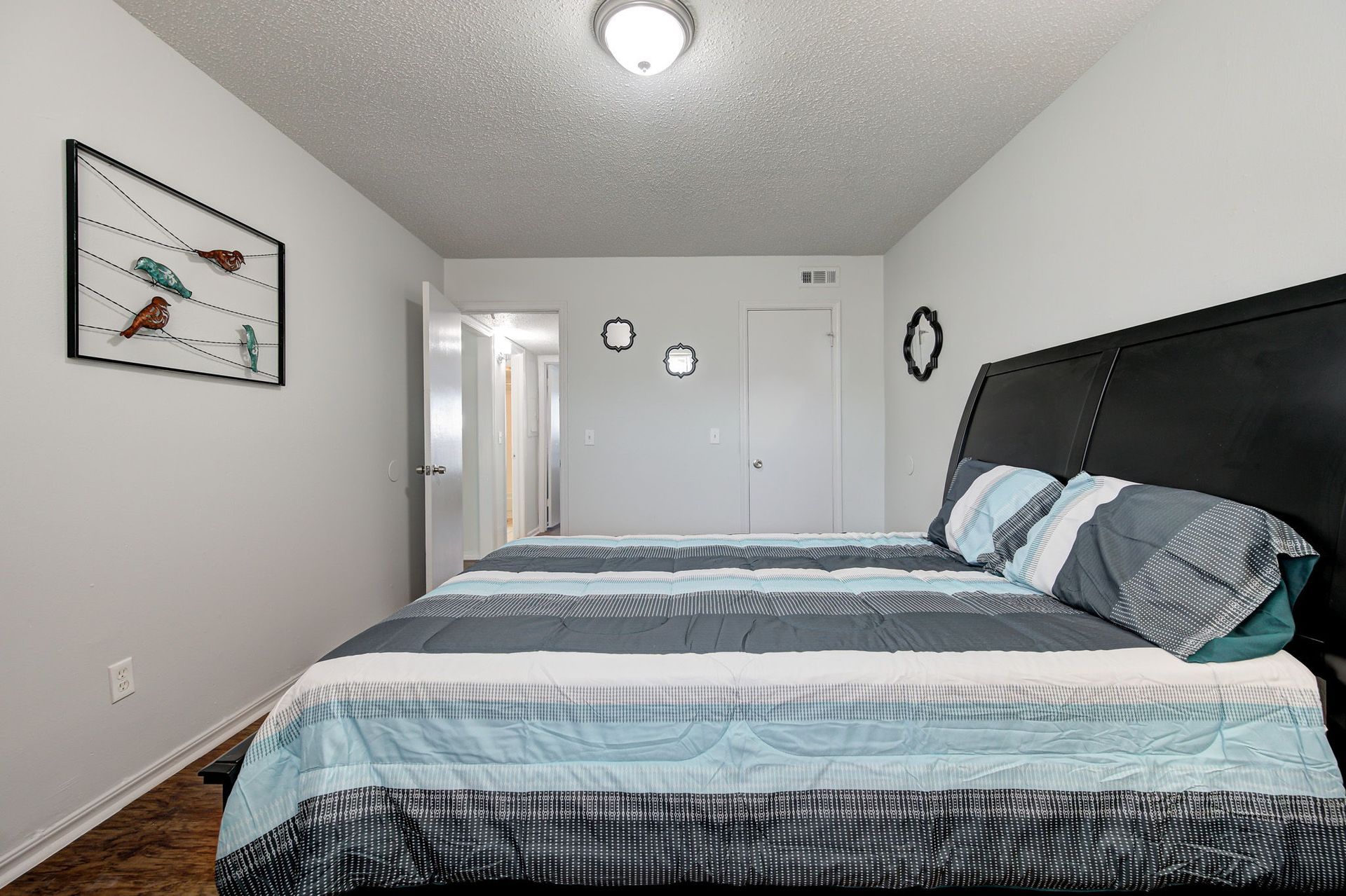 A bedroom with a large bed and a picture on the wall.