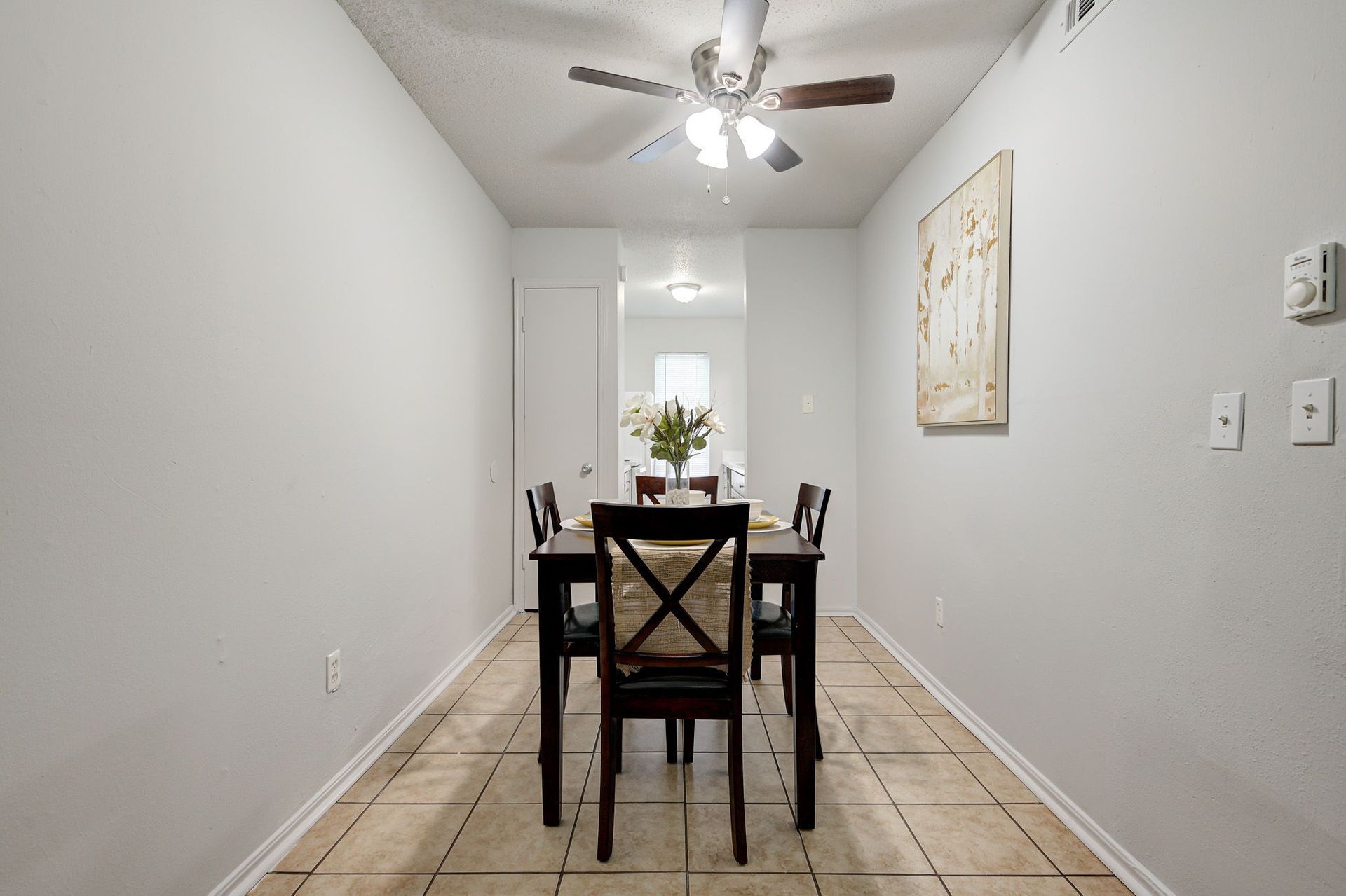 A dining room with a table and chairs and a ceiling fan.